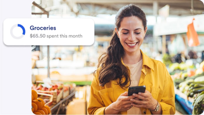 Woman reading grocery spending notification on a mobile phone.