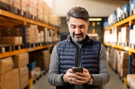 Man viewing phone in warehouse