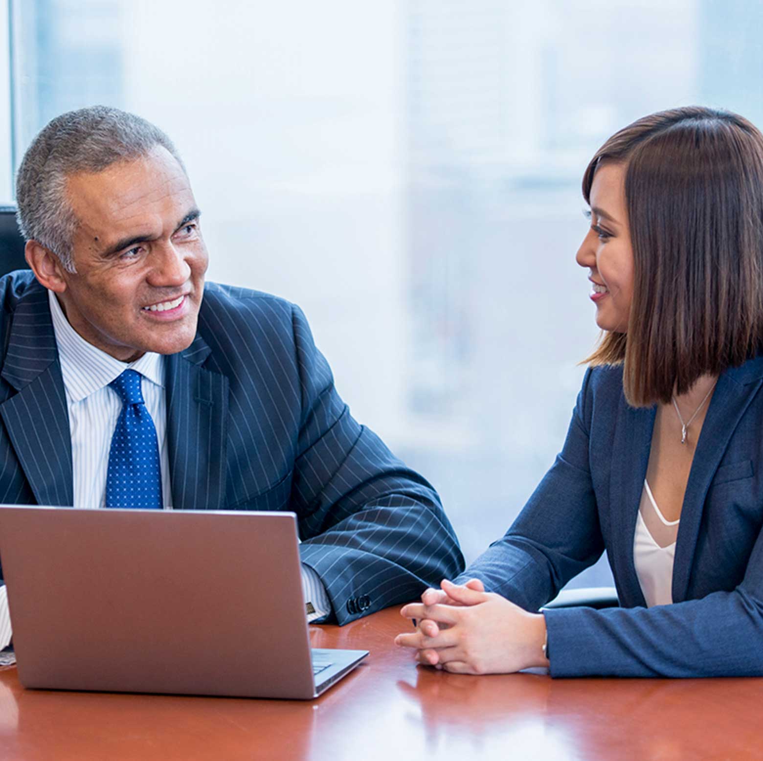 Three professional people standing in front of a large window and looking at a notepad