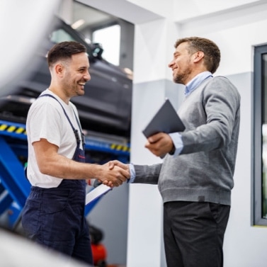 Two people shaking hands in mechanic garage