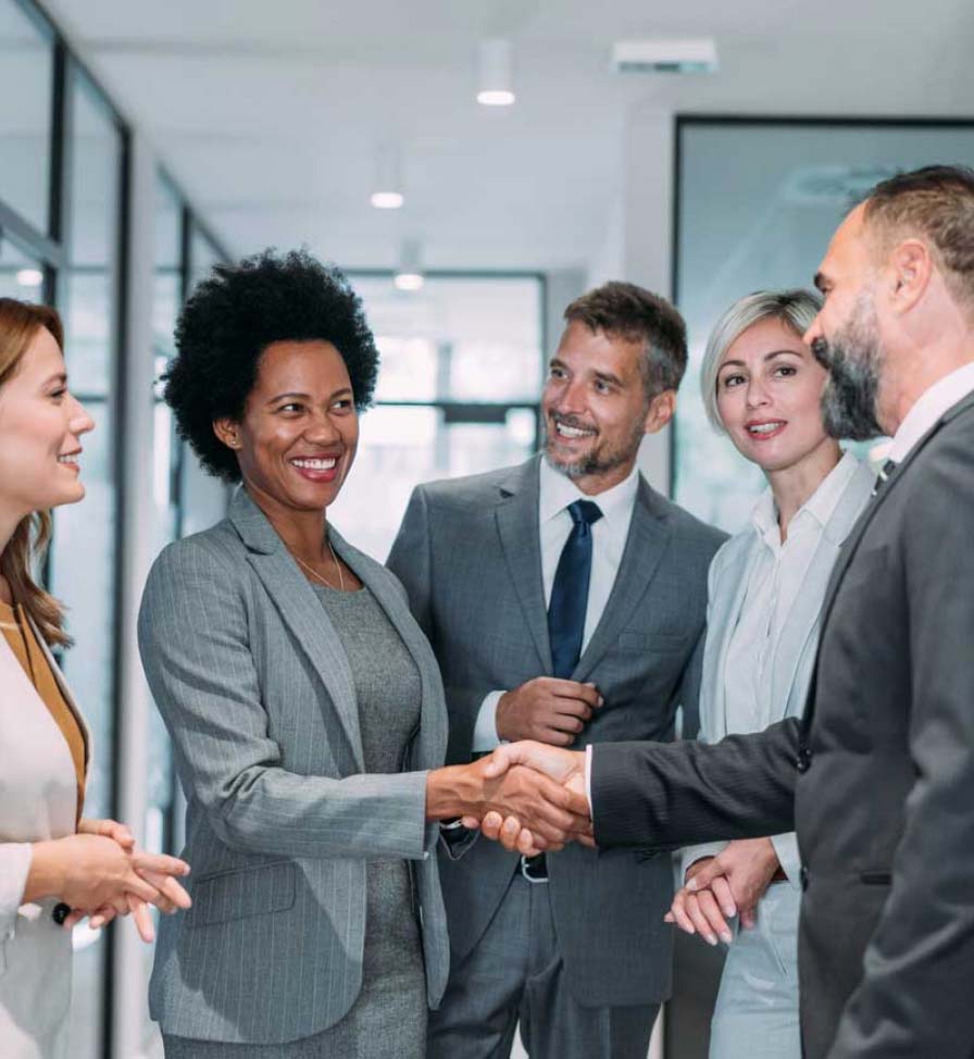 Male and female coworkers dressed in business suits greeting each other in an office