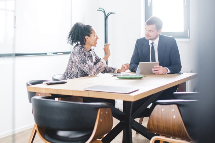 Professionally dressed man and woman sitting at a conference table