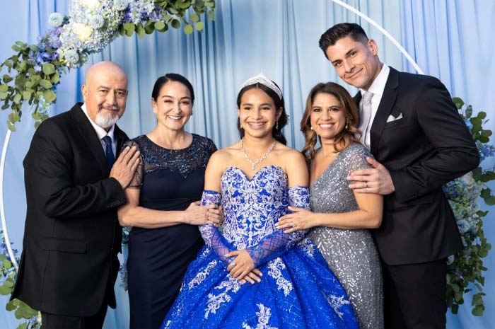 Tres generaciones de una familia hispana posan para una foto en la fiesta de quinceañera de una joven.