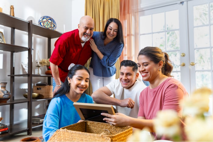 Una familia hispana desembala una caja y miran juntos una foto.