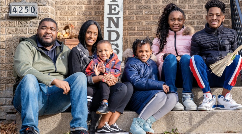 La familia Dismukes de seis integrantes se fotografía sonriente para un retrato; se mudaron a su nueva vivienda en 2020 después de trabajar con Acts Housing.